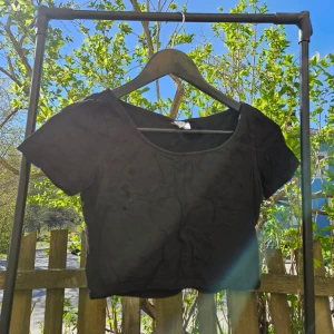 Svart croppad t-shirt - En svart croppad t-shirt med rund halsringning och korta ärmar. Perfekt för varma dagar eller att styla lager på lager. Enkel och stilren design som passar till det mesta.