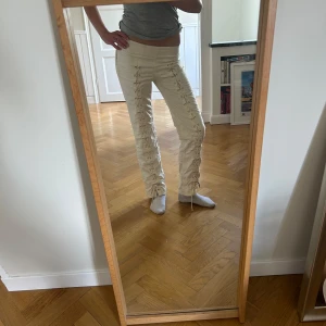 Beiga byxor med snörning - Snygga, trendiga och eftertraktade beiga byxor med dekorativ snörning längs hela framsidan av benen. Byxorna har en rak passform och medelhögmidja. Jag är 173 cm och de passar mig perfekt😊