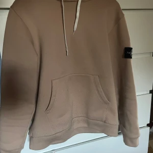 Beige hoodie från Stone Island - Säljer en beige hoodie från Stone Island med klassisk logotyp-patch på ärmen. Tröjan är äkta men badgen utbytt!! Fick den av min kusin och den har inte kommit till användning, saknar tyvärr kvitto och orginal badge