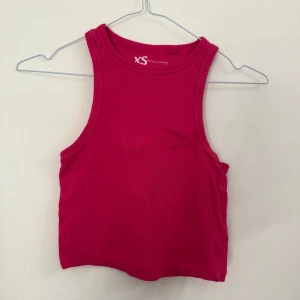 Rosa ribbad linnetopp - Säljer en enkel och snygg rosa ribbad linnetopp i storlek XS. Toppen har ärmlös design och rund halsringning, perfekt för varma dagar eller som layering-piece.