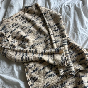 Beige och blå stickad kofta från Boohoo - Säljer en beige stickad kofta från Boohoo med blått mönster. Koftan har lång ärm och är perfekt för lager-på-lager. Mjuk och skön att ha på sig, passar till många olika outfits.