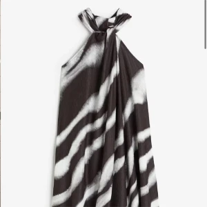 Svartvit halterneckklänning med zebramönster - Säljer en svartvit klänning med halterneck och öppen rygg. Klänningen har  zebramönster och är tillverkad i ett lätt, flödande material. 