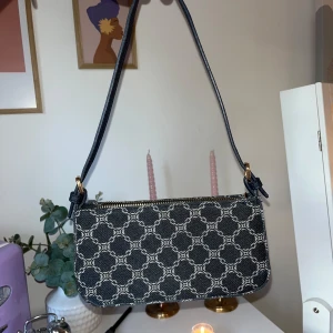 Mönstrad axelväska med dragkedja - Säljer en supersöt axelväska med vitt geometriskt mönster och guldfärgad dragkedja. Väskan är knappt använd och är u ett superfint skick💖💖