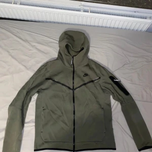 Nike Tech Flecce grön - Säljer denna gröna Nike tech flecce tröja som är i bra skick och hyfsat nyköpt. Nypris 1 200kr. Ett perfekt alternativ för sena sommarkvällar, till våren/hösten, en bekväm tröja när man är hemma.