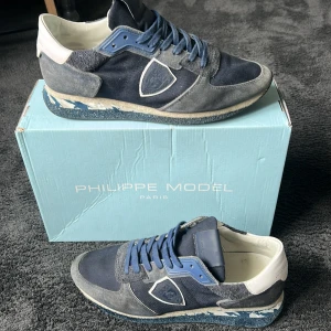 Philippe Model TRPX Low Man sneakers blå - Snygga Philippe Model TRPX Low Man sneakers i olika nyanser av blått med grå detaljer, även reflex detaljer. Box får man med här tyvär inte kvar kvittot. nästan oanvända lite smutsiga på vita delen av sulan (enkelt att fixa) bra skick. Sällsynd model ”nypris 4500” pris kan diskuteras 😇🙏