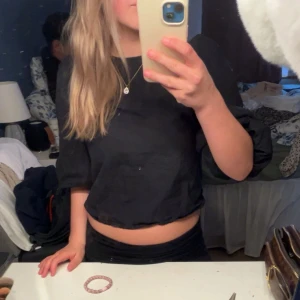 Svart croppad topp med rosett i ryggen - Säljer en svart croppad topp med trekvartsärm och två rosetter i ryggen. 
