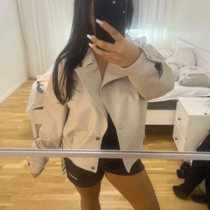 Beige skinnjacka med silverknappar - Säljer en beige skinnjacka med klassisk krage och silverfärgade knappar. Oanvänd. Funkar som en trenchcoat 