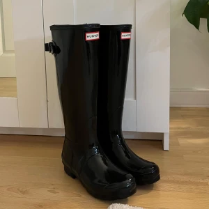 Svarta Hunter stövlar  - Säljer mina trendiga svarta blanka stövlar från Hunter!! Bara använd en gång då de tyvärr var för små för mig 💛Storlek 36!! Köpta på Stadium Outlet och har därför små defekter som dock knappt märks (se sista bilden)