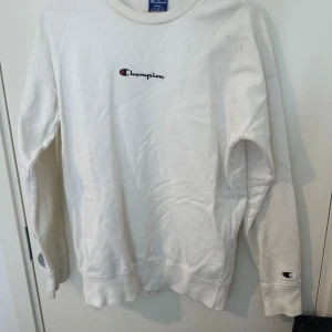 Vit sweatshirt från Champion, Small - Vit sweatshirt från Champion i storlek Small. Klassisk stil med broderad Champion-logga på bröstet och liten logga på ärmen. Rund hals och långa ärmar, tillverkad i mjuk bomull. Perfekt för chill dagar och enkel att matcha med jeans eller joggers.