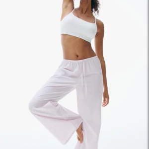 Randiga rosa pyjamasbyxor - Luftiga pyjamasbyxor i vitt med tunna rosa ränder. Byxorna har breda ben, elastisk midja. Tillverkade i mjuk bomull som känns skön mot huden.