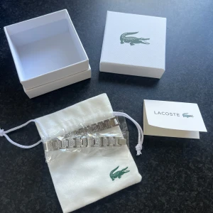 Lacoste armband  - Lacoste Bracelet (Silver)  • Condition: Brand new - no scratches, no damage • Color: Silver • Material: Stainless Steel • Length: 19 cm (adjustable - like a watch) Included: Everything shown in the ad • Original Lacoste box • Lacoste bracelet • Dust bag • Lacoste shopping bag • Digital receipt shown in the ad  Purchased from the official Lacoste website — you can see this on the receipt shown in the ad. If you have any questions, feel free to ask!