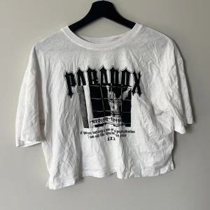 Vit Paradox t-shirt med tryck - Säljer en vit t-shirt från Paradox med svart grafiskt tryck och text framtill. Storlek M 