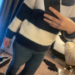 Randig stickad tröja från Lindex XS - Mysig stickad tröja från Lindex i storlek XS. Tröjan har breda marinblå och vita ränder, lång ärm och rund hals. Tillverkad i en mjuk blandning av återvunnen polyester, ull och elastan. Perfekt för dig som gillar en chill och stilren look.