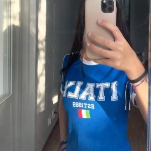 Blå Italy t-shirt med tight passform - Snygg blå t-shirt. Modellen är tight och har vita detaljer vid hals och ärmslut. Köpt på Gina Tricot för 260 kr i storlek S och är aldrig använd. Prislappen är kvar. 