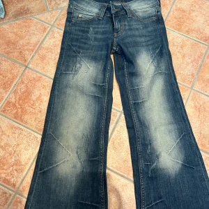 Blå bootcut jeans från Cheap Monday - Säljer ett par blå bootcut low waist jeans från Cheap Monday med slitna detaljer och snygg tvätt. Ny köpta å aldrig användts. Strl: 26/30