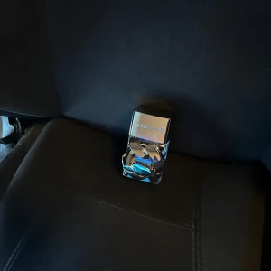 Michael Kors Pour Homme EDP - Aldrig använd. Snygg parfymflaska från Michael Kors med spegelblankt silverlock och coolt kedjemönster i metall runt glasflaskan. Flaskan är genomskinlig och har en modern, lyxig design som verkligen sticker ut i badrumshyllan.