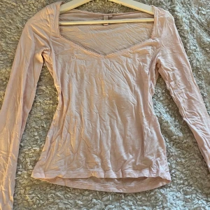 Ljusrosa långärmad topp  - Ljusrosa tröja med spets kant längst v-ringningen från Nelly i storlek S, använd ett fåtal gånger