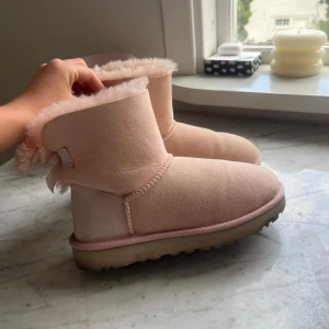 Ljusrosa UGG bailey bow - Intressekoll på mina älskade Ugg bailey bow i ljusrosa. De är nästintill oanvända och har endast några få små tecken på användning som kan skickas vid förfrågan. Just denna färg finns inte att köpa längre och kommer därav endast att sälja vid bra pris🌸