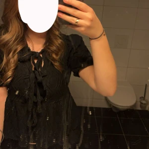 Svart blus med knyt från Gina Tricot - Supersöt svart blus från Gina Tricot med puffärmar och tre knyt framtill. Normal i storleken
