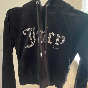 Juicy Couture hoodie i svart velour  - Svart hoodie i mjuk velour från Juicy. Tröjan har huva, långa ärmar och snörning framtill och är lite kortare nertill som en magtröja. ❤️Jättesnygg och bra skick💕storlek xs men passar även S