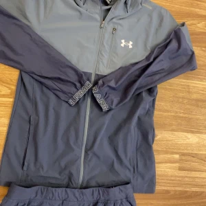 Mörkblå träningsbyxor Under Armour -  bara träff!!Mörkblå träningsbyxor från Under Armour med elastisk midja och logga på benet. Byxorna har smal passform, resår vid benslut och är tillverkade i ett lätt syntetmaterial som andas. Perfekta för träning eller chill. Och pris kan diskuteras dm bara träff!!