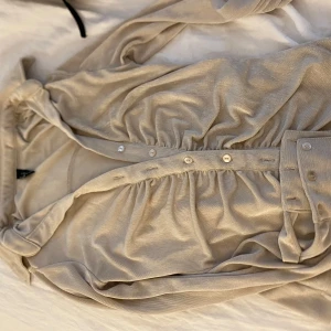 Beige blus med knappar - Supersnygg beige blus med knappar framtill och markerad midja. Perfekt för dig som gillar stilrena och eleganta plagg.