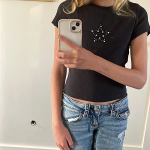 Svart croppad topp med pärlstjärna - Svart croppad topp med korta ärmar och en snygg stjärndetalj av pärlor och paljetter. Säljer denna eftersom den är inte riktigt min stil längre 💞