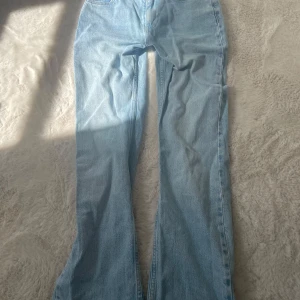Ljusblå bootcut jeans - Säljer ett par ljusblå jeans från gina i storlek 34. Modellen har bootcut-ben eller straight och klassisk femficksdesign. Jeansen är tillverkade i denim och har en snygg, tidlös look som passar till det mesta.