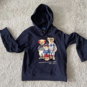 Mörkblå hoodie Polo Bear Ralph Lauren - Mörkblå polo bear hoodie från Ralph lauren i storlek 10-12 år. Perfekt för kommande höst,winter och vår🍁❄️🍃 Köptes i London i en Ralph lauren butik för 1700kr. Är i jättebra skick inga defekter eller skador. Original förpackning följer med. Skriv vid funderingar🧩