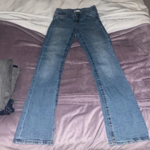 Lågmidjade Blå jeans från Gina Tricot - Säljer ett par snygga blå jeans från Gina Tricot. De har en klassisk femficksdesign och stängs med två knappar framtill. Perfekta för en avslappnad stil. Storlek 164 som passar som en XS. Pris kan diskuteras.