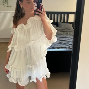Vit klänning med volanger- Lovisa Wallin NAKD  - Säljer en superfin vit axelbandslös klänning med volanger från Lovisa Wallins kollektion för NAKD!Klänningen har en luftig passform och är tillverkad i ett lätt material som ger en härlig känsla. Passar perfekt för en dag eller kväll ute. 🌸 Kläningen är storlek 38 men skulle säga att den passar bra även för någon som brukar ha 36 men även större! 