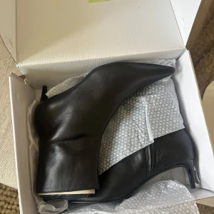 Svarta läderstövletter med stilettklack - Snygga svarta stövletter i läder med spetsig tå och stilettklack. Material i läder. Helt nya och oanvända, kvar i sin box! Storlek 39. Nypris 1199kr.