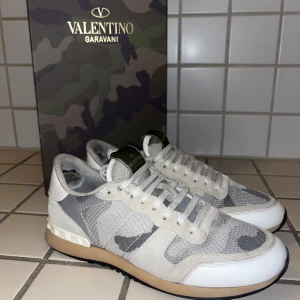 Valentino skor rockrunners - Snygga Valentino Garavani sneakers i ett stilrent camouflage-mönster. Skorna har en kombination av grå och vita nyanser med klassisk snörning. Perfekta för dig som vill ha en unik och trendig look. Defekt på bild 5 då det är lite grått där fram köpta från trendwardrobe på plick. Kommer med box