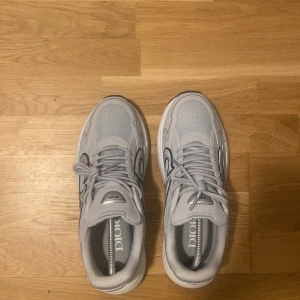 Grå sneakers från Dior - Snygga grå sneakers från Dior med en stilren design. Skorna har snörning och en robust sula för extra komfort. Perfekta för en trendig look.