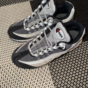 Nike Air Max sneakers i grå och svart - Snygga Nike Air Max sneakers i en stilren kombination av grått och svart med vita detaljer. Skorna har en klassisk Air Max-sula för extra komfort och stil. Perfekta för både vardag och träning.