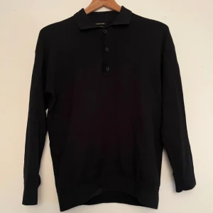 Svart pikétröja från Massimo Dutti - Säljer en stilren svart pikétröja från Massimo Dutti i extrafin bomull. Tröjan har långa ärmar och tre knappar framtill. Perfekt för en elegant och avslappnad look. Tröjan har användes få tal gånger och är i nyskick.