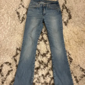 Blå lågmidjade bootcut jeans - Snygga blå bootcut jeans med klassisk femficksdesign och ljus tvätt. Perfekta för en avslappnad stil. De har en knapp- och dragkedjestängning framtill. W29 L32. passar som XS/S
