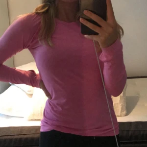 Rosa långärmad tröja - Säljer en rosa långärmad tröja med en tight passform. Perfekt för en avslappnad stil eller träning. Tröjan är enkel och stilren, vilket gör den lätt att matcha med olika outfits. Den har hål för tummarna i ärmen💕