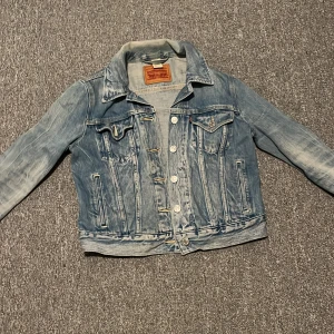 Blå jeansjacka från Levi's S dam  - Säljer en klassisk blå jeansjacka från Levi's med knappar framtill och två bröstfickor. Perfekt present till en tonårig tjej.  Priset är inte spikat i sten Storlek S 