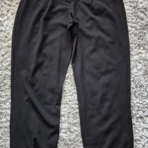 Svarta byxor från JDY - Snygga svarta byxor från JDY med elastiska muddar vid bensluten. Perfekta för en avslappnad stil. Byxorna har en bekväm passform och är tillverkade i ett mjukt material. Går ej att förhandla, priset är fast