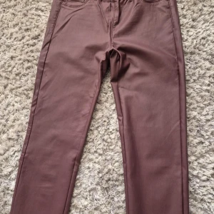 Bruna byxor från Sirup - Snygga bruna byxor från Sirup med elastisk midja för extra komfort. Byxorna har en stilren design med fickor både fram och bak. Perfekta för en avslappnad men ändå stilfull look. Går ej att förhandla, priset är fast