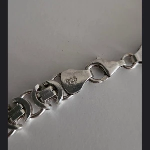 Silverhalsband med kedjedesign - Säljer ett stilrent silverhalsband med en unik kedjedesign. Halsbandet är stämplat med 925, vilket indikerar att det är tillverkat av äkta silver. Perfekt för att ge en elegant touch till din outfit.