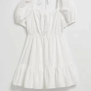 Vit klänning med puffärmar - Jag säljer nu min vita klänning med puffärmar och broderade detaljer. Klänningen har en knytning i ryggen och en volangkant nedtill. Endast använd 1 gång. Perfekt för studenten eller konfirmationen! Nypris 790 kr men säljer för endast 500 kr.