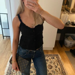 Topp med spetsdetaljer - Supersöt svart ärmlös topp med spetsdetaljer och knappar framtill💗Storlek XS