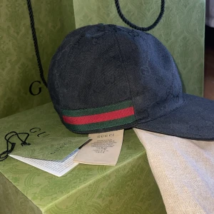 Svart keps från Gucci - Snygg svart keps från Gucci med det ikoniska gröna och röda bandet på sidan. I princip helt ny använd några enstaka gånger! Inköpt på GUCCI i Stockholm. Nypris 5.650kr. 