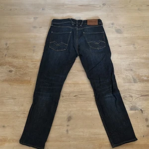 Mörkblå jeans från Replay - Snygga mörkblå jeans från Replay i modellen Anbass. De har en slim fit och klassisk femficksdesign med dragkedja och knapp. Perfekta för en stilren look. Modellen är också omsydd så på längden är det kanske 30/31