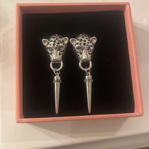 Silvriga örhängen med leopardhuvud - Snygga silvriga örhängen med leopardhuvuddesign och spetsiga hängen. Perfekta för att ge en djärv touch till din outfit. Endast testade en gång! (Kommer ej i asken)
