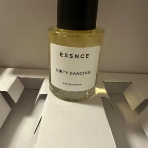 Essnce Dirty Dancing Eau de Parfum - Upptäck Essnce Dirty Dancing Eau de Parfum, en elegant doft i en stilren glasflaska med svart lock. Perfekt för den som vill ha en sofistikerad och modern parfymupplevelse.