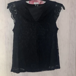 Svart spetsblus från Pieces/veromoda - Elegant svart spetsblus från Pieces/veromoda med v-ringning och vackra spetsdetaljer på ärmarna. Perfekt för en stilren look.