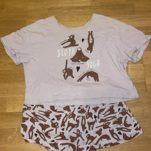 Ljuslila pyjamas med sengångare från SoU - Säljer en ljuslila pyjamas från SoU med ett gulligt sengångarmotiv. Pyjamasen är uppdelad i enT-shirten och ett par shorts. Den är gjord i ett väldigt mjukt material.
